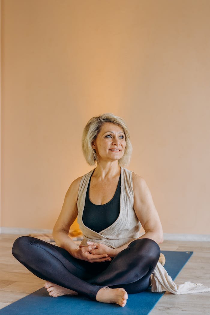 Elderly Woman Sitting on Blue Yoga Mat